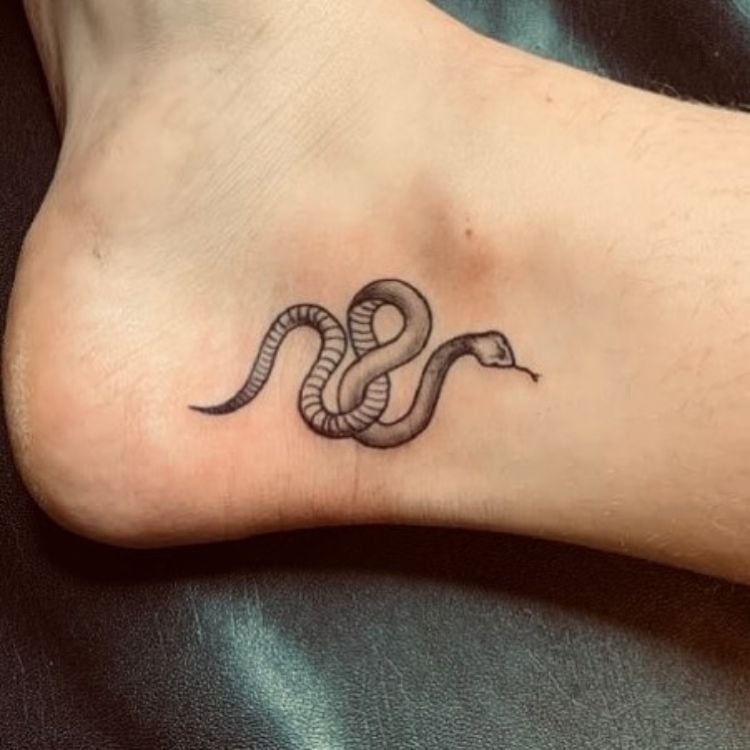 uma tatuagem pequena de cobra no pé, próximo ao tornozelo