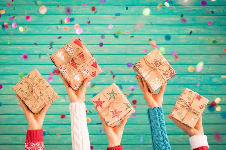 foto de quatro mãos segurando caixas de presente de Natal para amiga