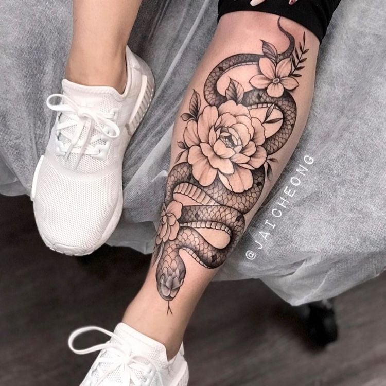uma tatuagem na canela com uma cobra e várias rosas