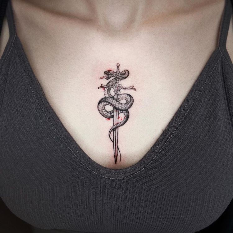 uma mulher branca com uma tatuagem de cobra enrolada em uma espada