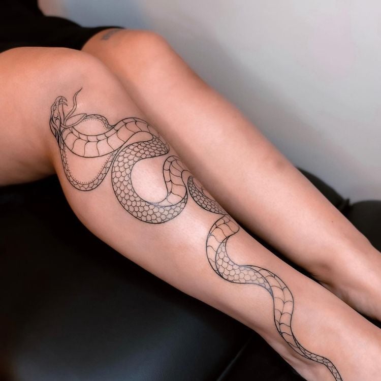 pernas femininas com uma cobra tatuada em uma delas