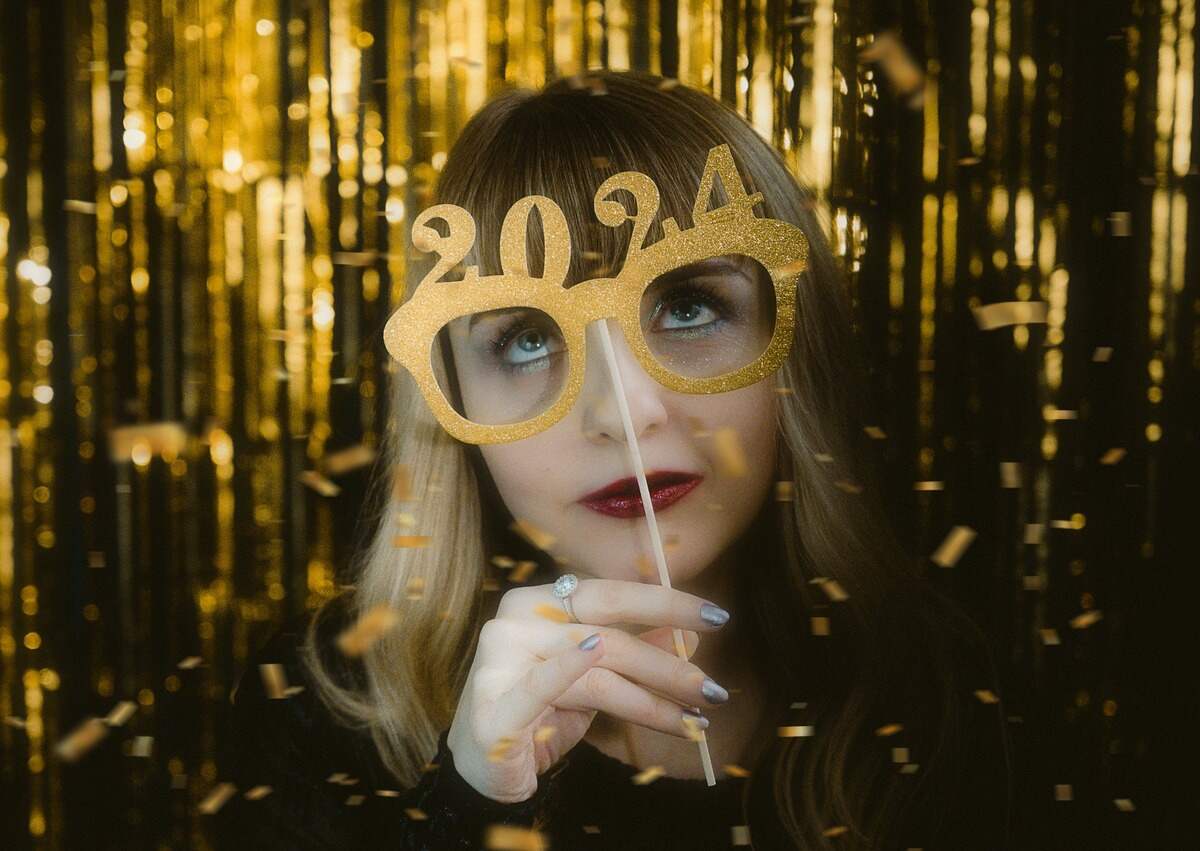 Menina loira com batom vermelho recebendo o ano novo usando um óculos com os números 2024