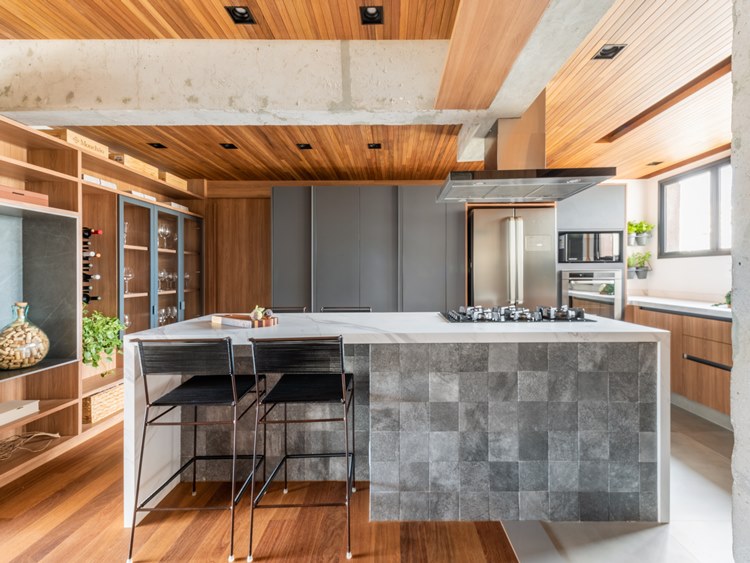 Cozinha de apê de 187 m² decorada pelo arquiteto Pietro Terlizzi, ilha do lado externo, com 2 banquetas pretas e textura piso pequeno cinza mesclado