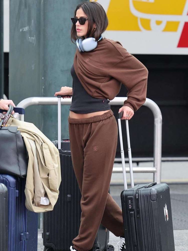 Bruna Marquezine usando conjunto de moletom marrom com blusa baby look preta, no aeroporto. 