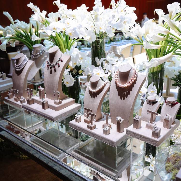 Decoração do almoço da joalheria Cris Porto com joias e jarros de vidro com orquídeas e copos de leite brancos
