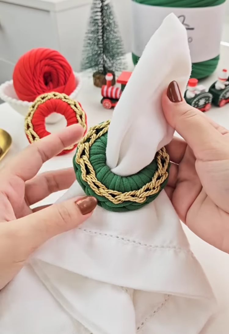Mãos segurando Porta guardanapo natalino de crochê verde com detalhe dourado