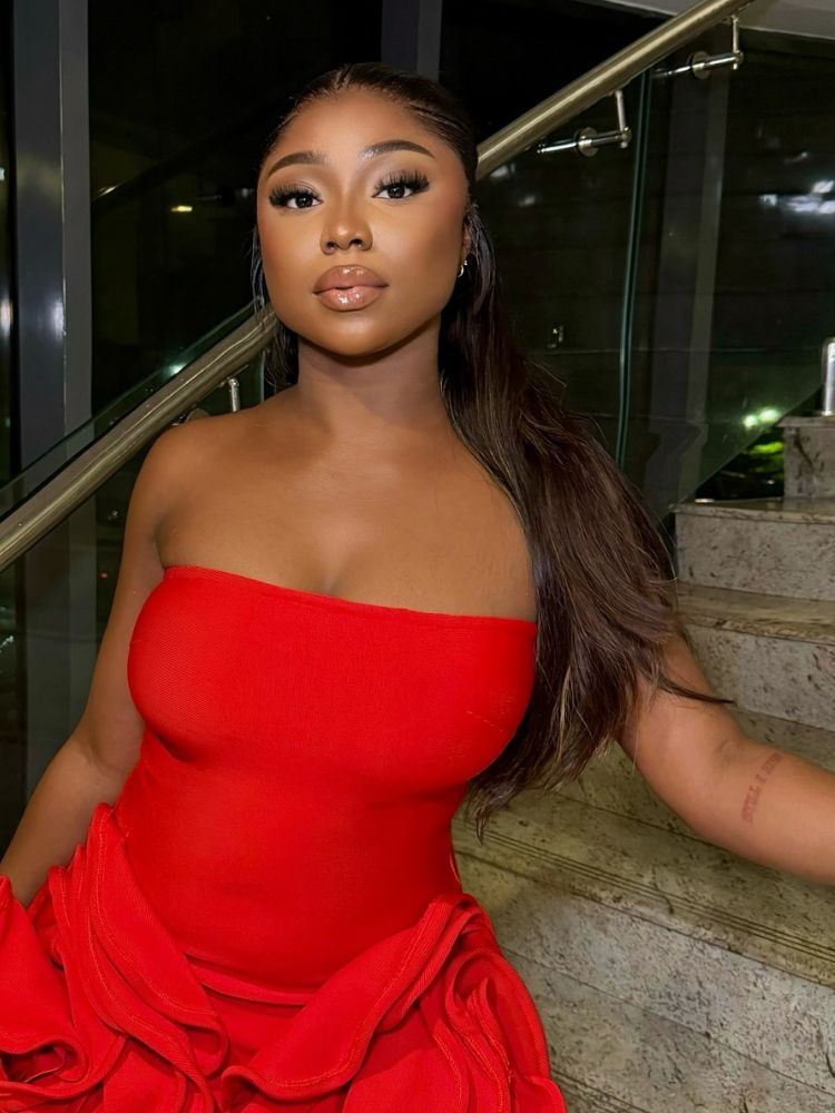 Mulher de pele negra usando maquiagem natural e vestido vermelho sem alça