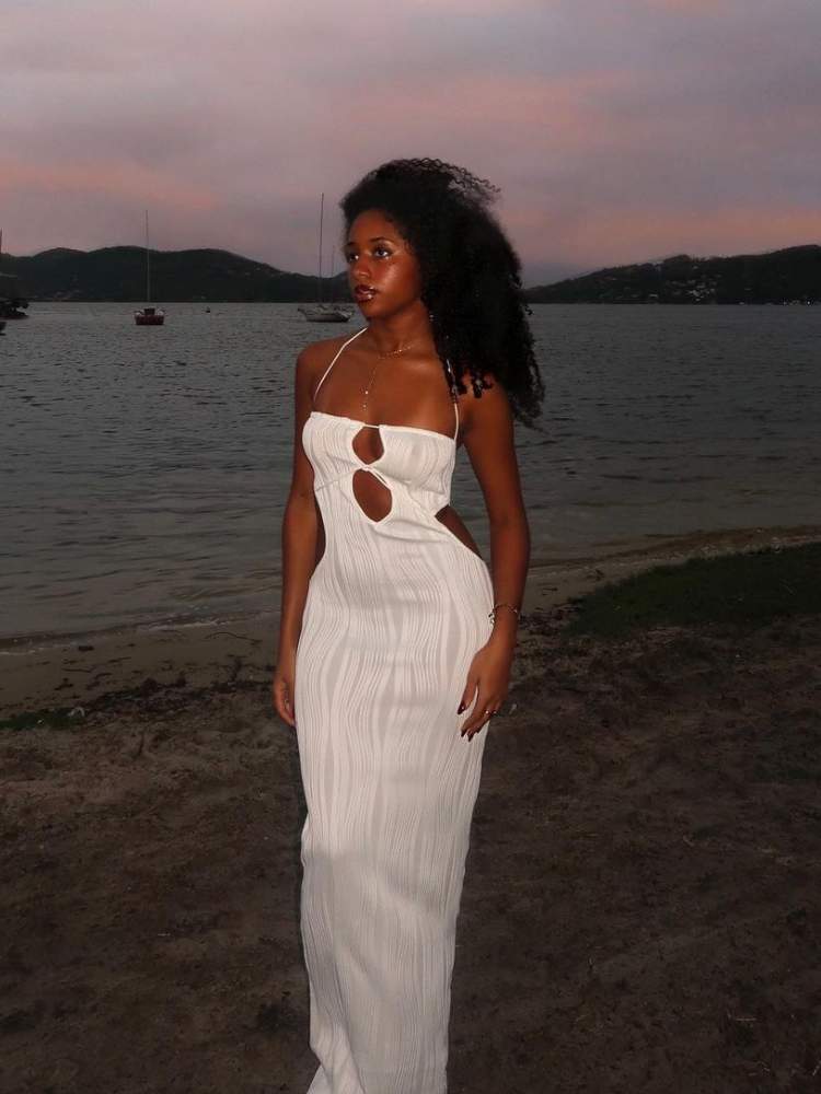 Mulher usa vestido longo branco como sugestão de roupa para ano novo na praia