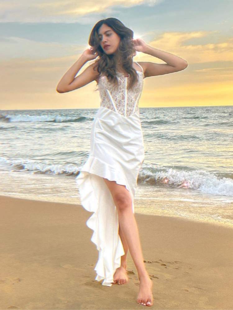Mulher usa vestido branco assimétrico como sugestão de roupa para ano novo na praia