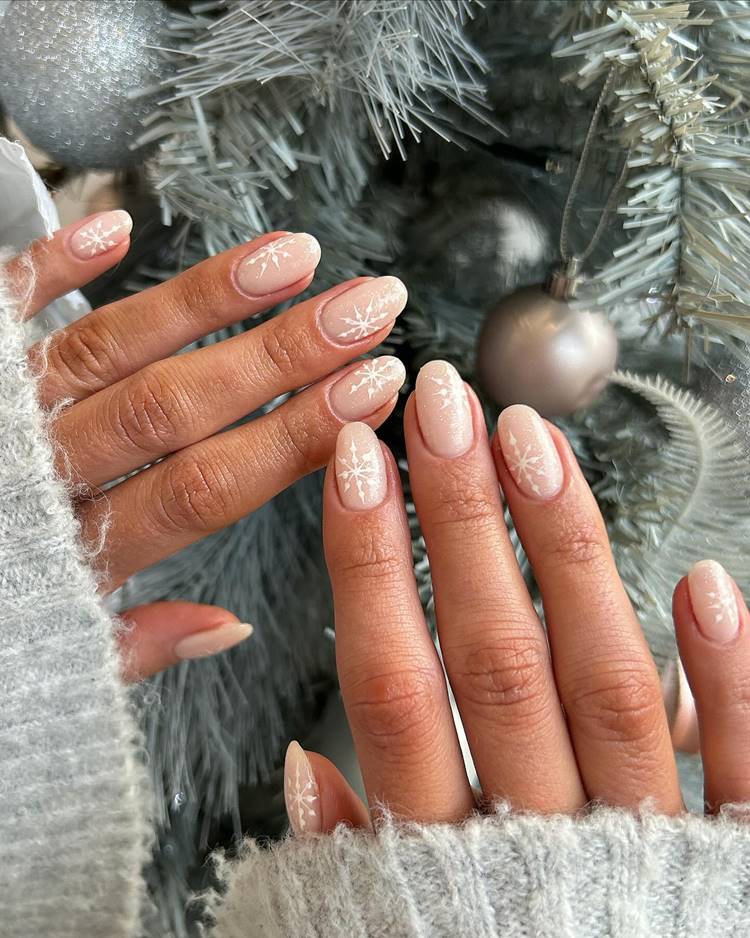 Mãos com unhas decoradas para Natal ou Ano Novo, com desenho de flocos de neve, cores claras