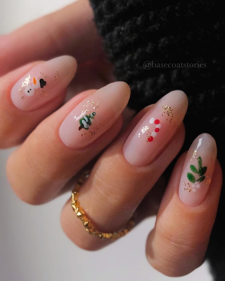 Mão com unhas decoradas para Natal, desenhos simples de boneco de neve, pinheiro, bengala natalina, planta visco branca