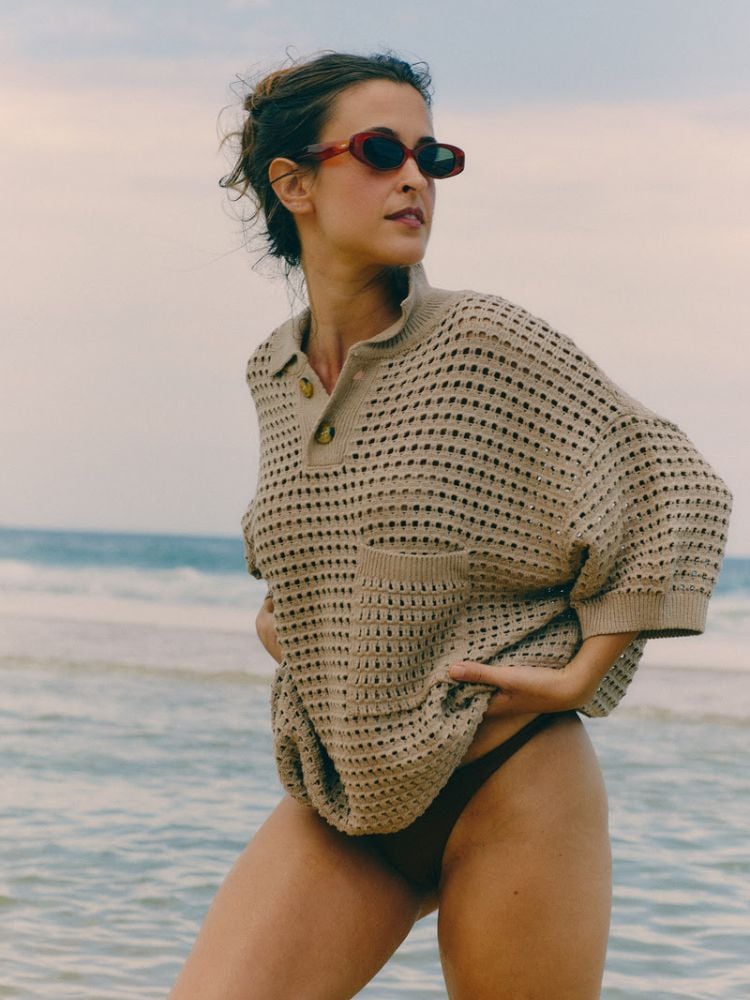 foto de mulher usando óculos de sol do modelo Rita, da collab entre as marcas Zerezes e Haight, e blusa de crochê bege com calcinha de biquíni marrom