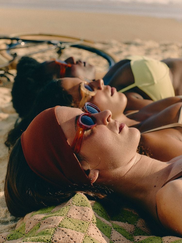 foto de três mulheres deitadas na areia da praia usando óculos de sol da collab entre as marcas Zerezes e Haight