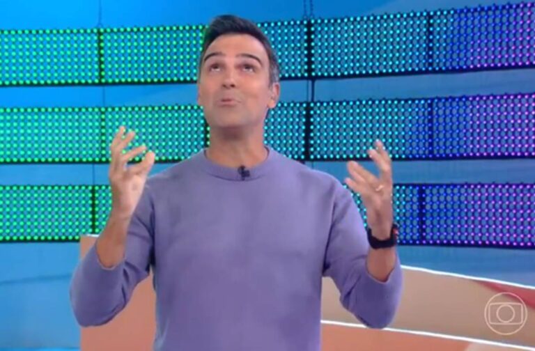 Com camisa lilás de manga longa, Tadeu Schmidt olha para o alto ao anunciar dinâmica para o Paredão