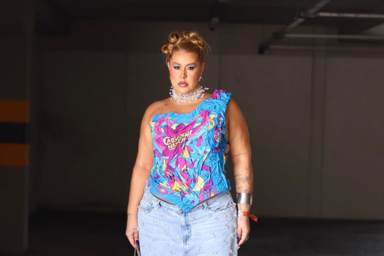 Mulher de pele morena usando abadá azul customizado em corset de ombro só, além de calça jeans