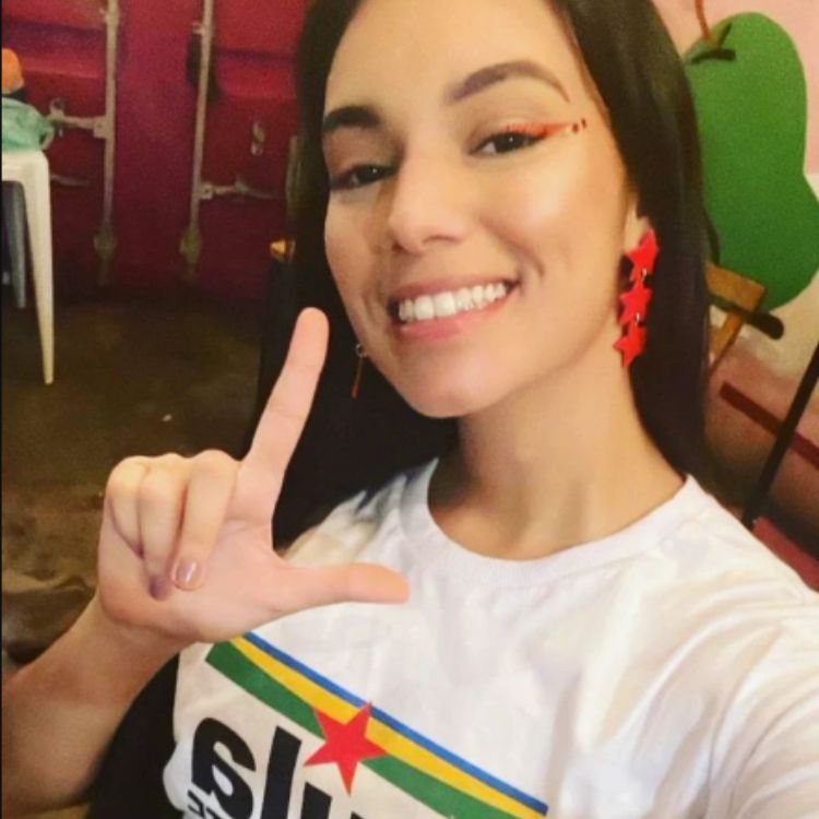 Foto mostra Alane Dias, participante do BBB 24, fazendo o L com uma das mãos enquanto veste uma camiseta do presidente Lula