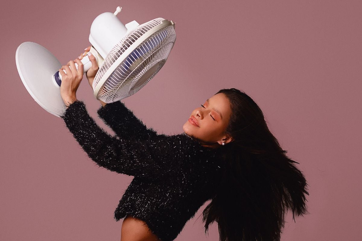 mulher segurando ventilador, simbolizando como fazer maquiagem durar no calor