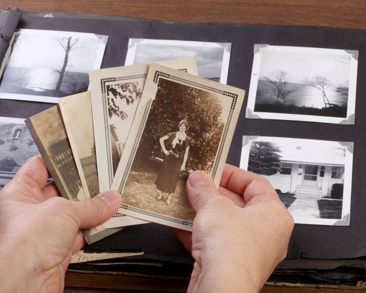 Fotografias antigas de pessoas e paisagens em álbum e mãos segurando outras