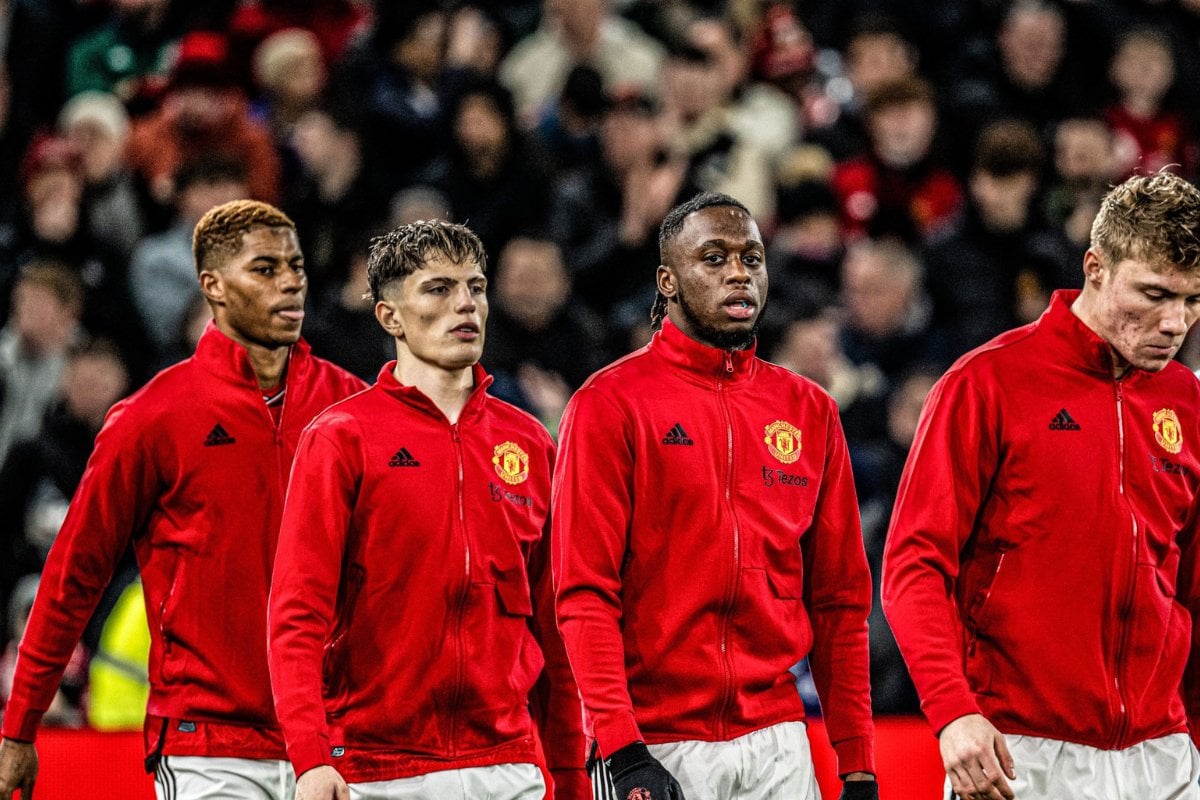 Jogadores do Manchester United de casaco vermelho com escudo do time