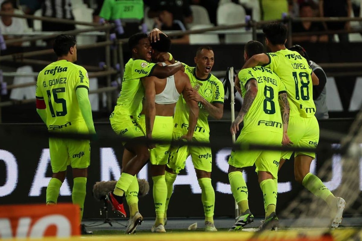Imagem de jogadores do Palmeiras comemorando próximos à torcida.