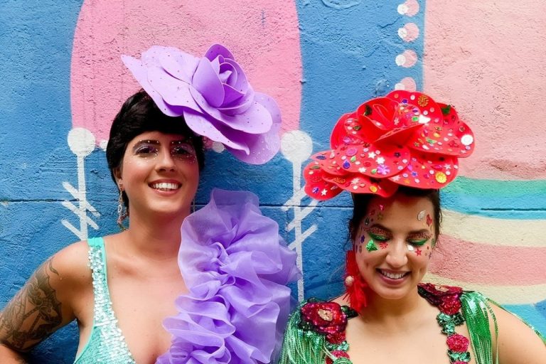 Foto de duas mulheres de pele clara fantasiadas de flores com makes de Carnaval, sendo com strass nos olhos e desenhos no rosto