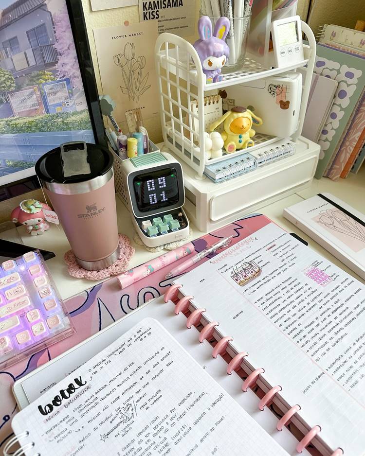 Material escolar em cima de mesa com computador, agendas cadernetas, copo Stanley relógio e outras Decorações