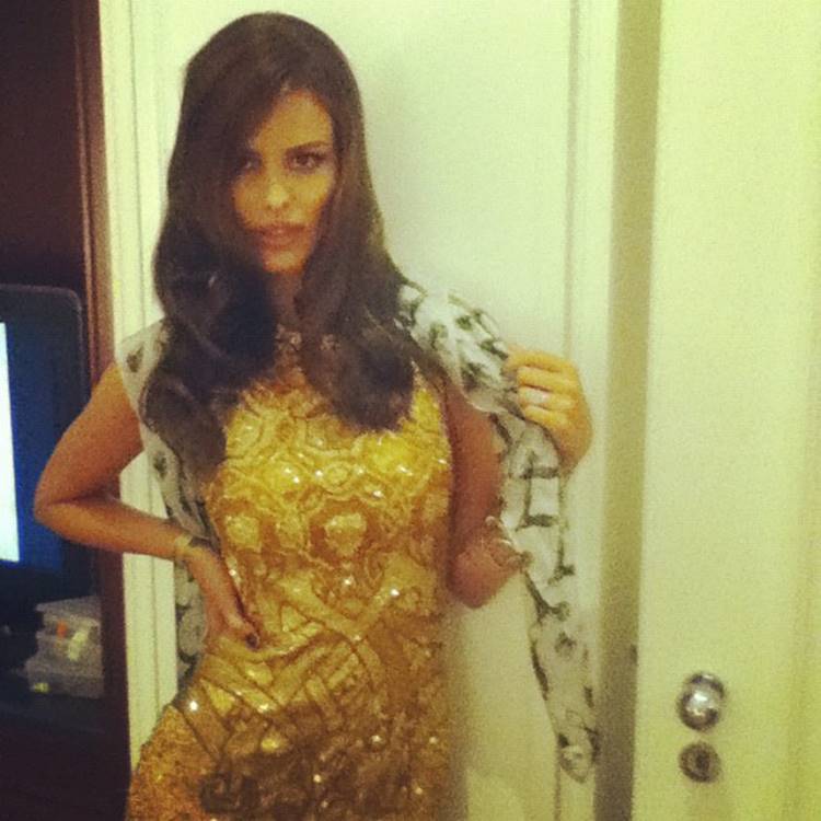 Antes e depois cabelo castanho da Yasmin Brunet: modelo usando vestido dourado com lenço em foto de frente à porta