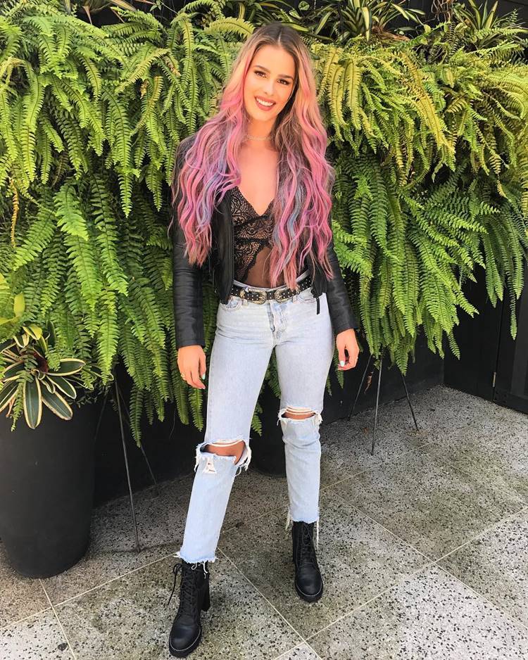 Antes e depois cabelo Yasmin Brunet: modelo usando em cropped preto de renda, calça jeans, jaqueta de couro, botas e seu cabelo é platinado com mechas rosas e azul