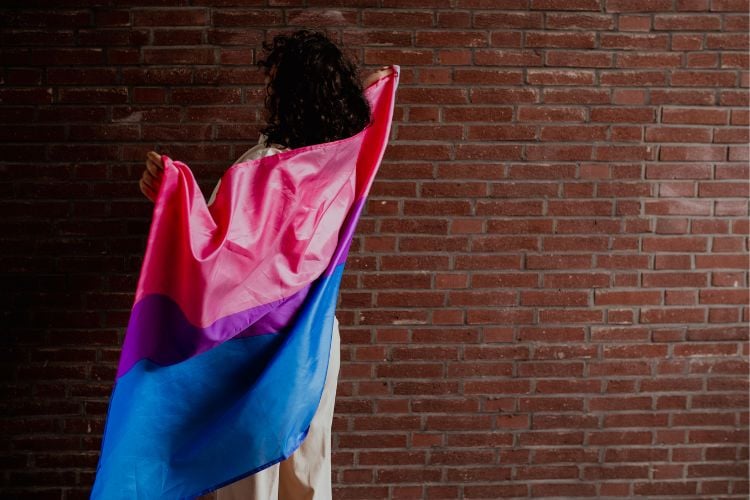 Pessoa de costas com bandeira bissexual, rosa, roxa e azul