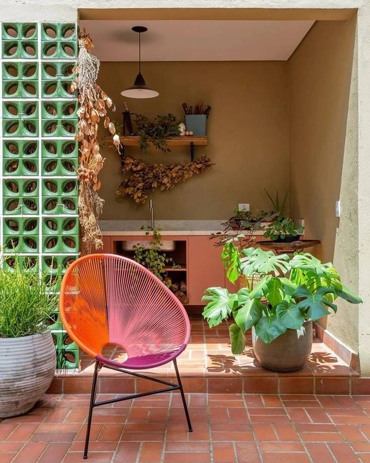 Jardim simples com cadeira colorida e vaso com plantas verdes