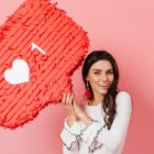 fundo rosa com mulher segurando piñata vermelha, simbolizando como comprar vizualizações Reels no Instagram