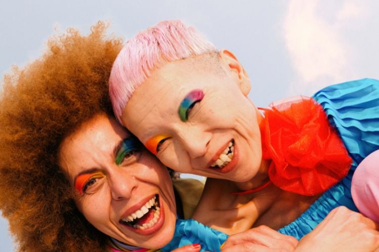 Duas mulheres maduras usando roupas coloridas e maquiagem arco-íris nos olhos