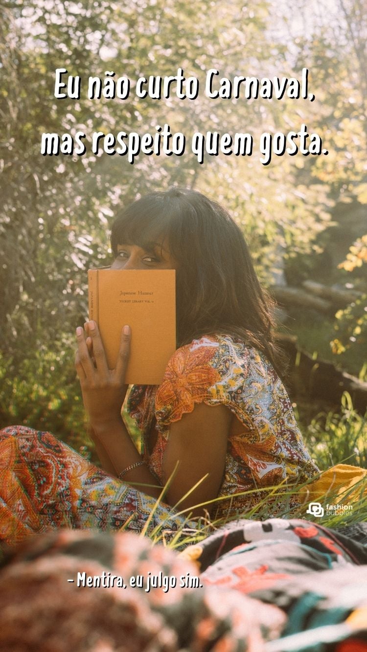Status anti-folia escrito em foto de menina de vestido com livro tampando sorriso sentada na natureza
