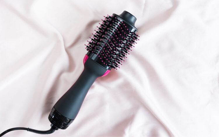 melhor escova secadora de cabelos posicionada em cima de tecido rosa claro