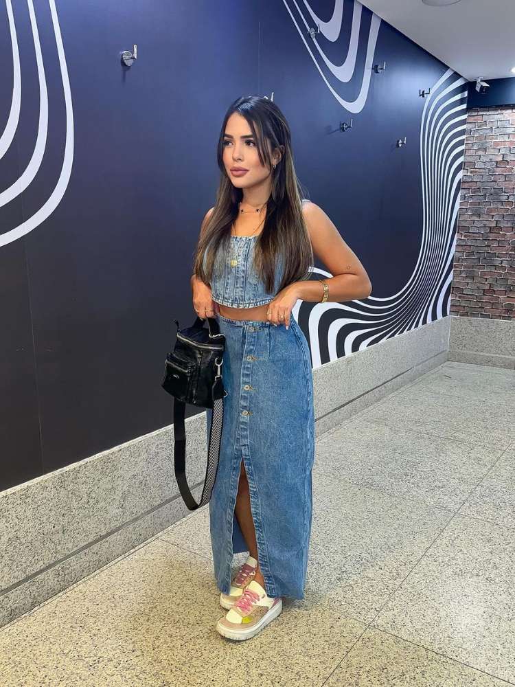 Mulher no shopping com cropped e saia longa jeans com fenda, além de tênis plataforma colorido