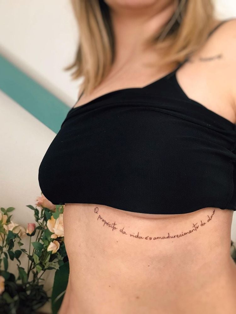 mulher com frases para tatuagem O propósito da vida é o amadurecimento da alma na costela
