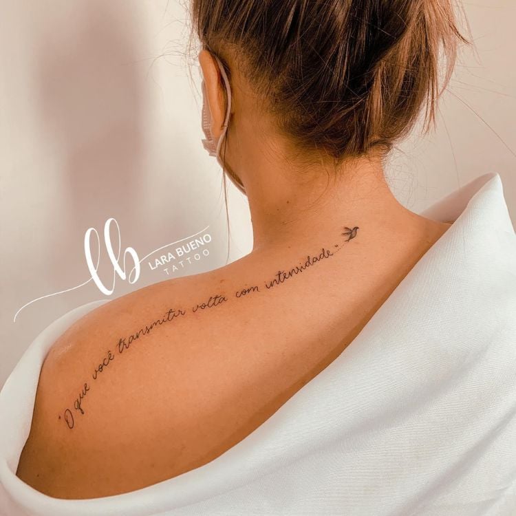 mulher com tatuagem delicada nas costas de frase O que você transmitir volta com intensidade