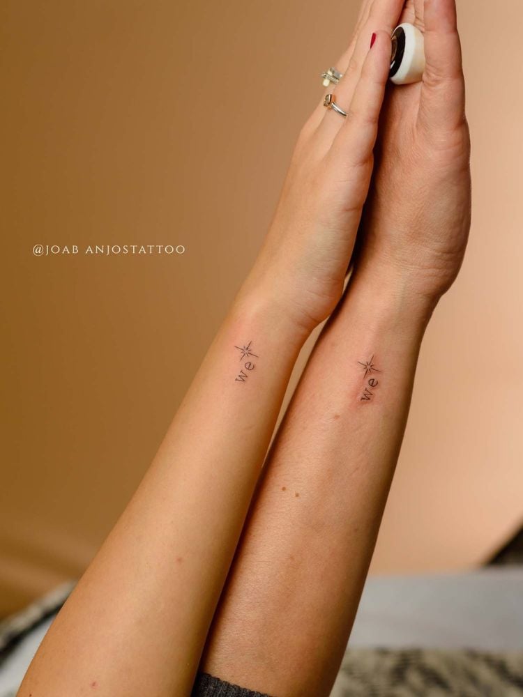 foto de dois braços com tatuagem fine line da palavra we, nós em inglês
