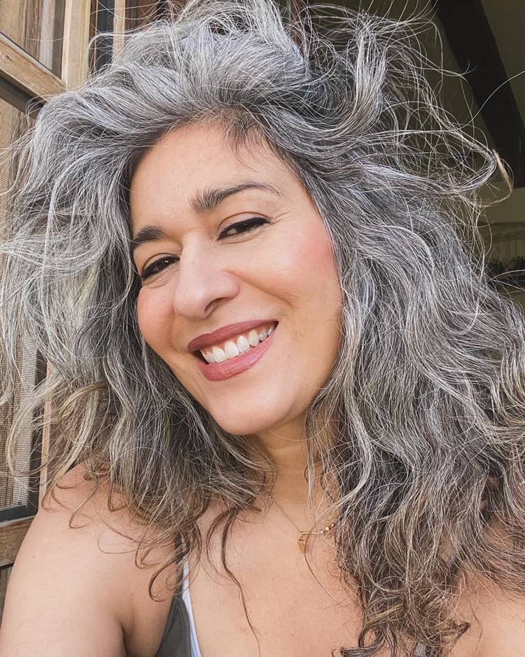 Mulher sorridente maquiada com cabelo grisalho