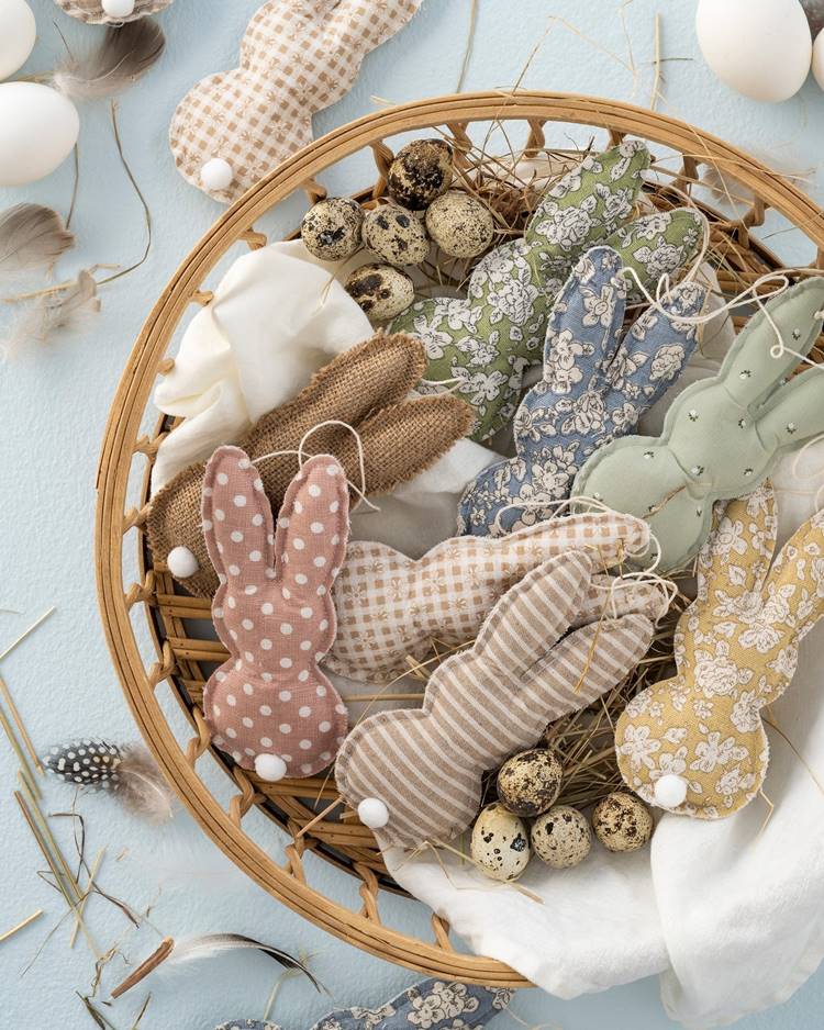 Cesta recheada de coelhinhos de tecido, cada um com detalhes únicos.