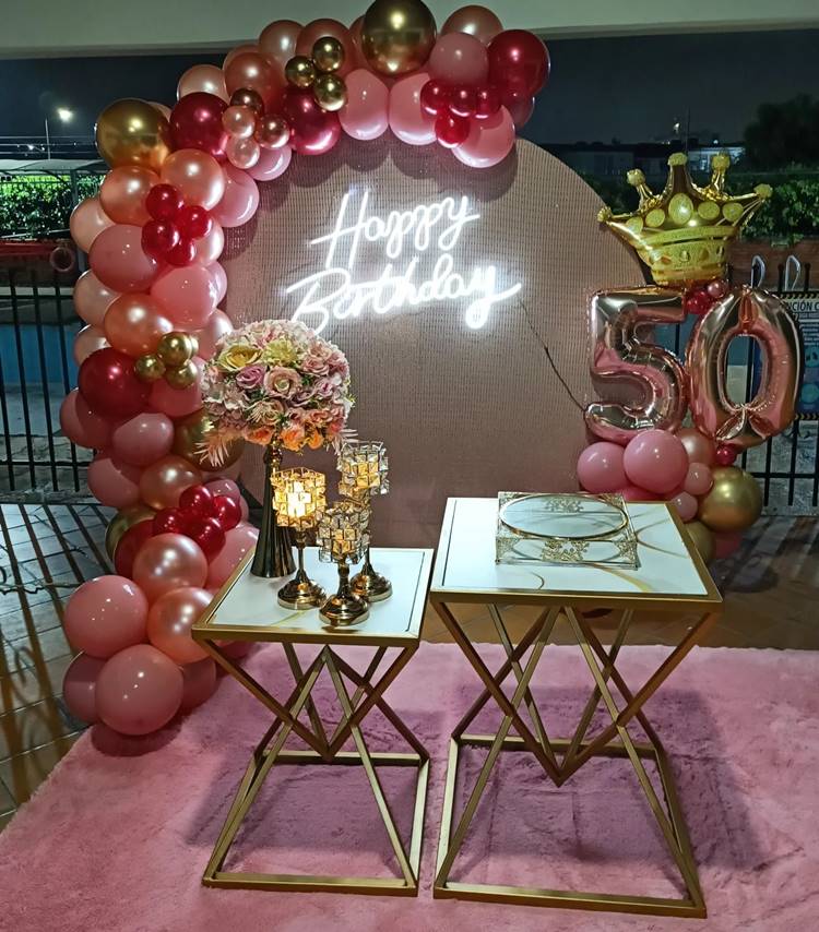  Painel redondo e decoração com balões e flores em tons de rosa.