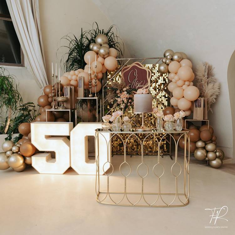 Tons de dourado e marrom, decorada com plantas verdes e rosas salmão.