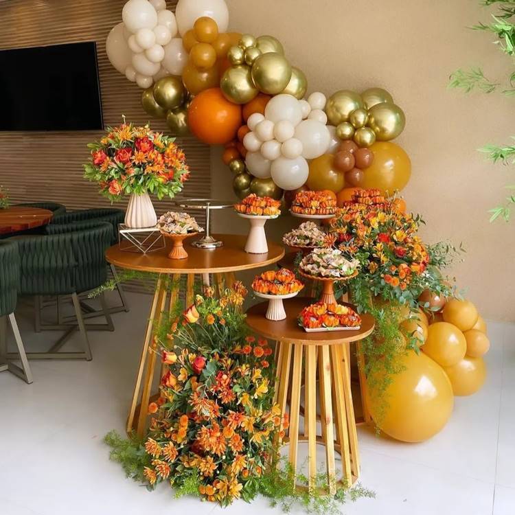 Decoração de aniversário Laranja e dourado com flores balões e doces dentro de casa
