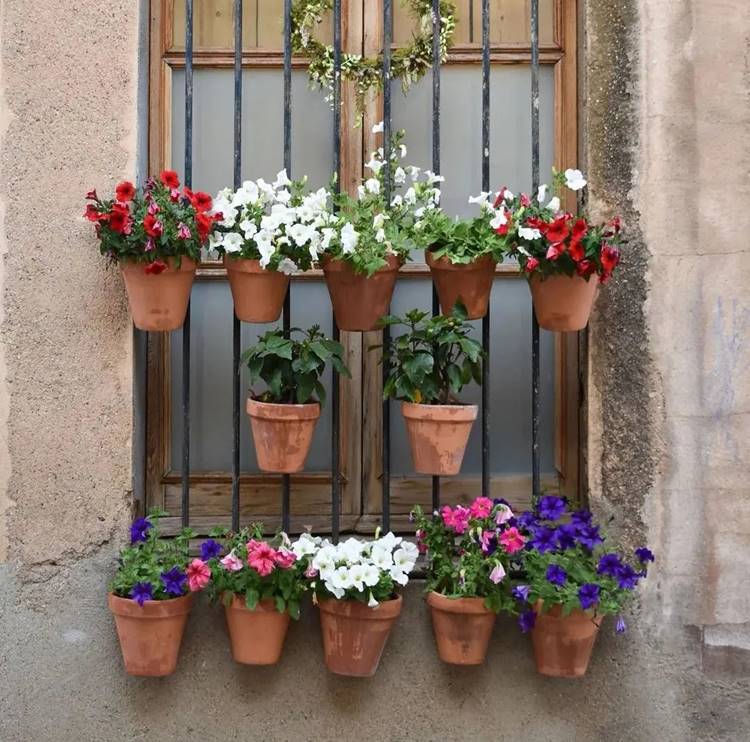 Jardim suspenso com vasos de barro em grade de janela
