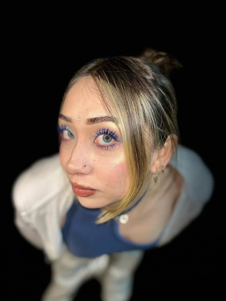 Menina loira de pele clara usando sombra azul clara nos olhos com máscara de cílios azul