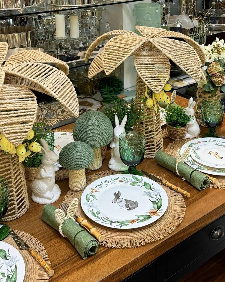  mesa posta para almoço de Páscoa chique com itens Verde trabalhados em palha pratos com pinturas de coelho
