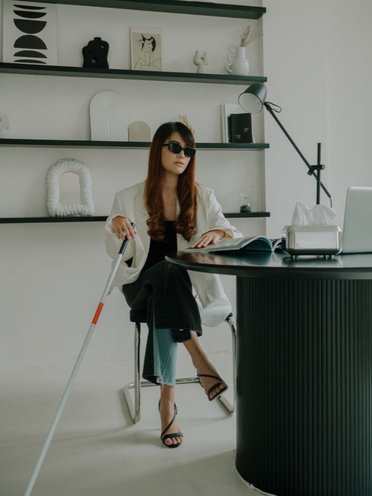 Mulher com deficiência visual, sentada em escritório decorado de preto e branco
