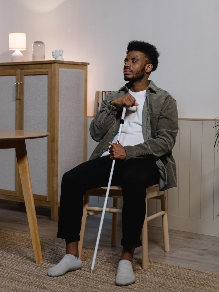 Homem com deficiência visual sentado em cadeira de madeira em espaço com móveis de madeira