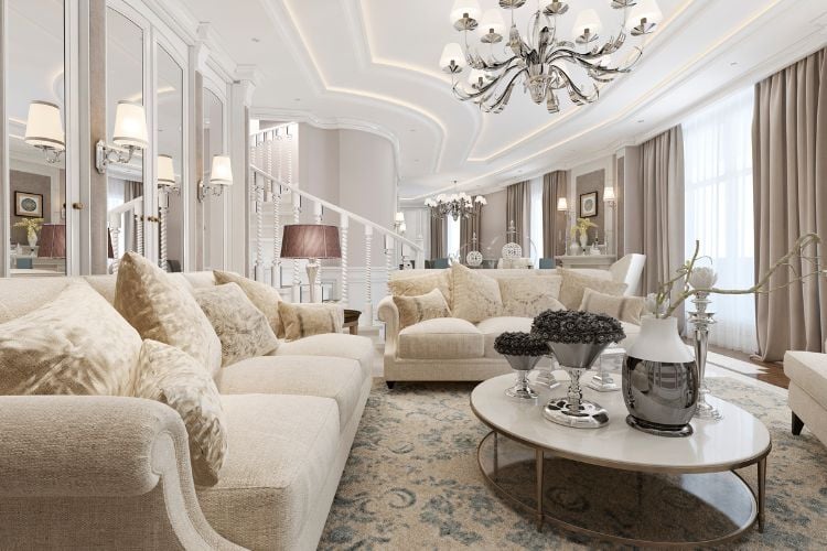 Sala com decoração clássica, com lustres, móveis robustos e redondos e tons neutros