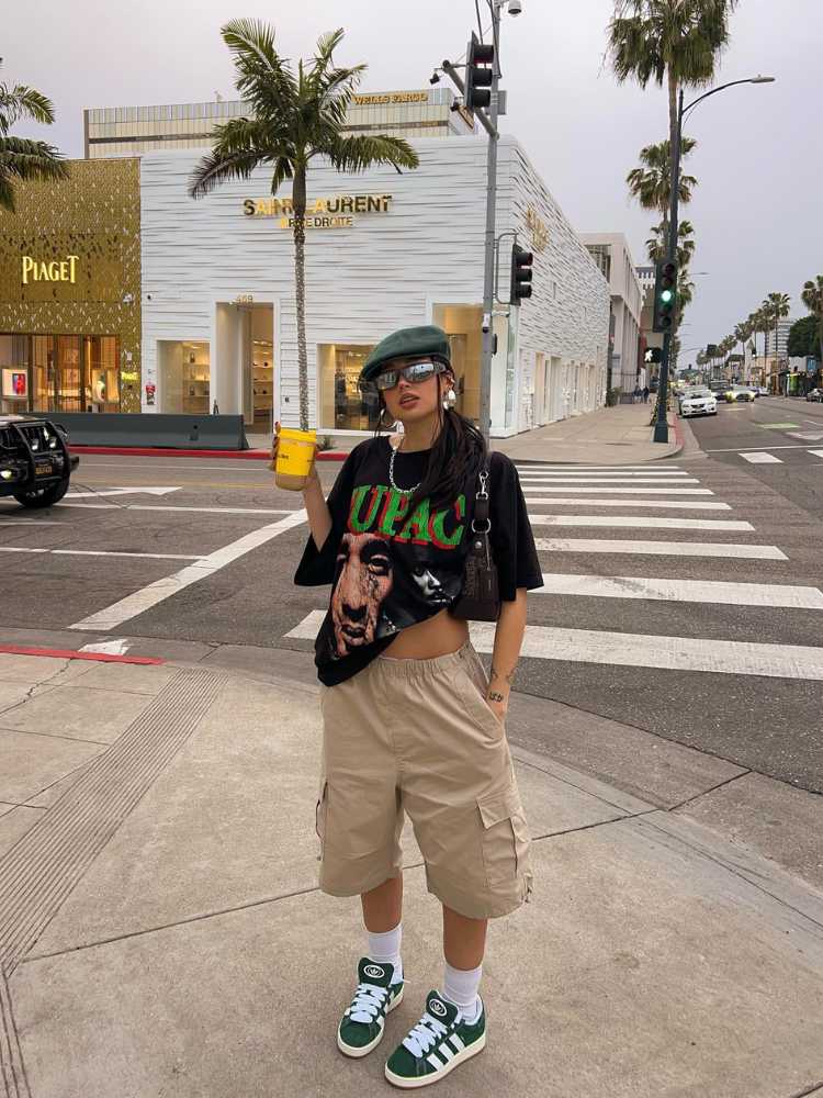Mulher asiática usando boina, blusa oversized do Tupac, shorts cargo bege e tênis